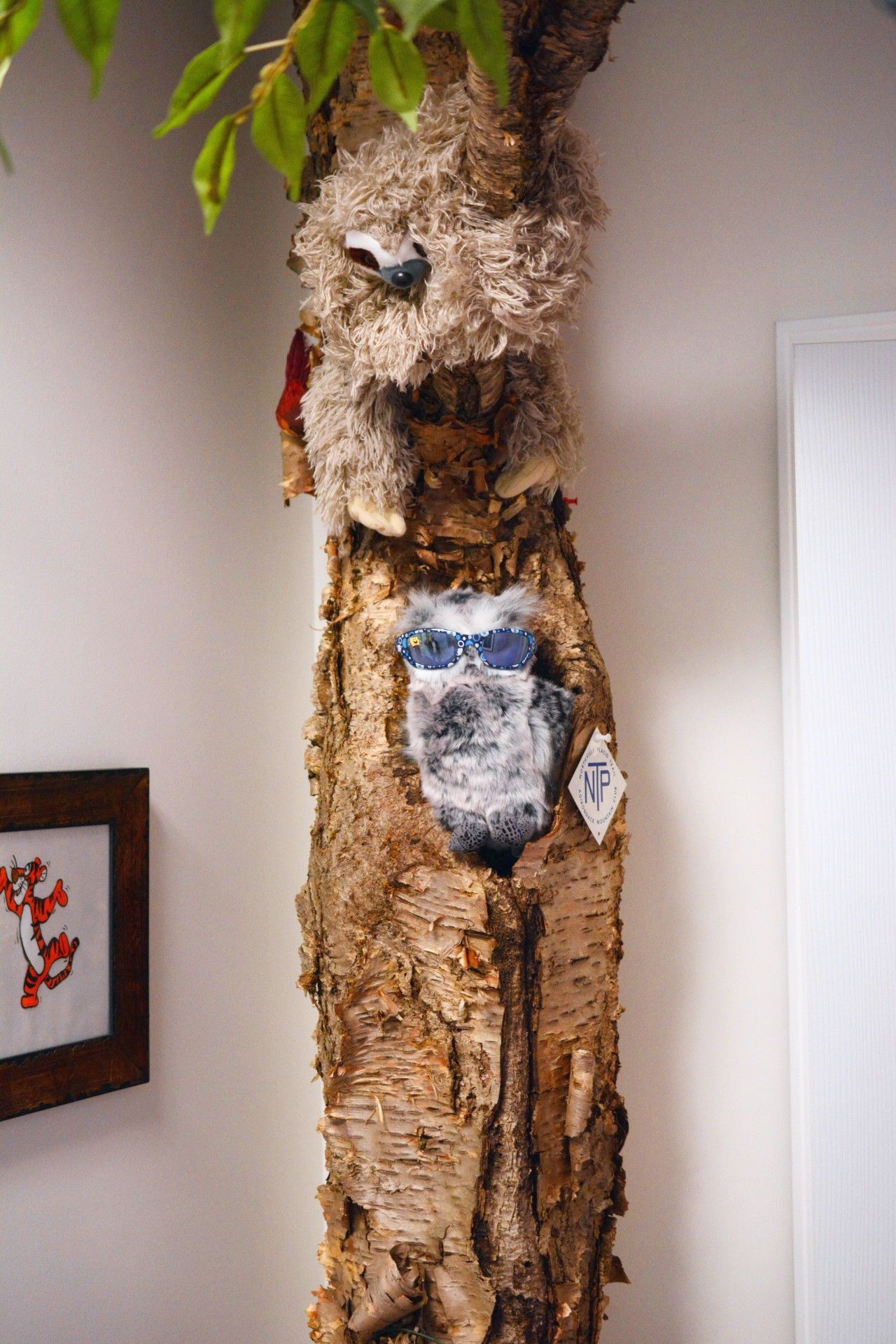 Tree trunk wall art with a carved owl face and leafy branches indoors