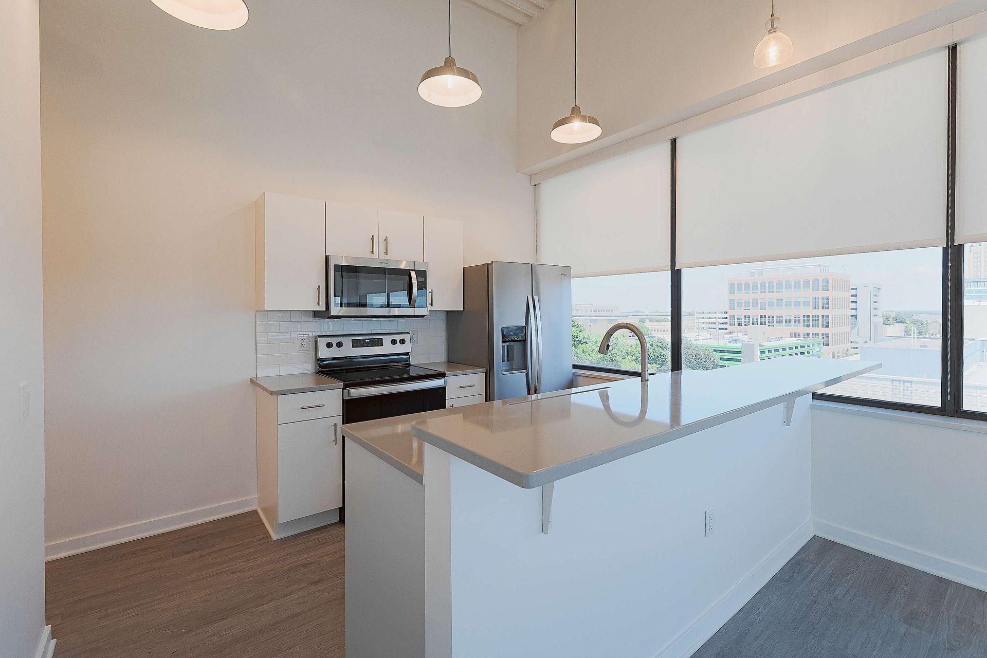 A kitchen with white cabinets , stainless steel appliances , a refrigerator and a sink.