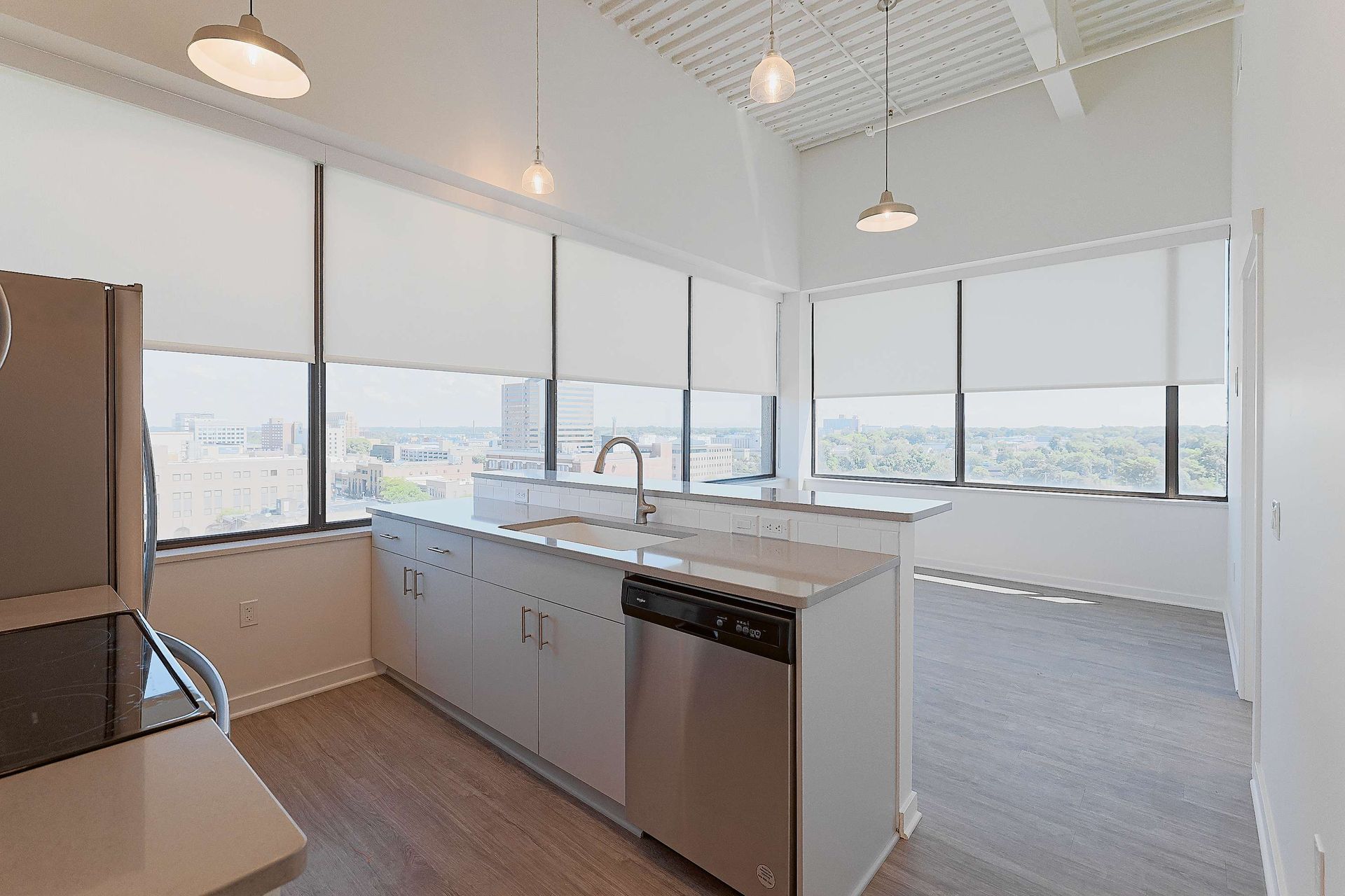 A kitchen with stainless steel appliances , a large island , and lots of windows.