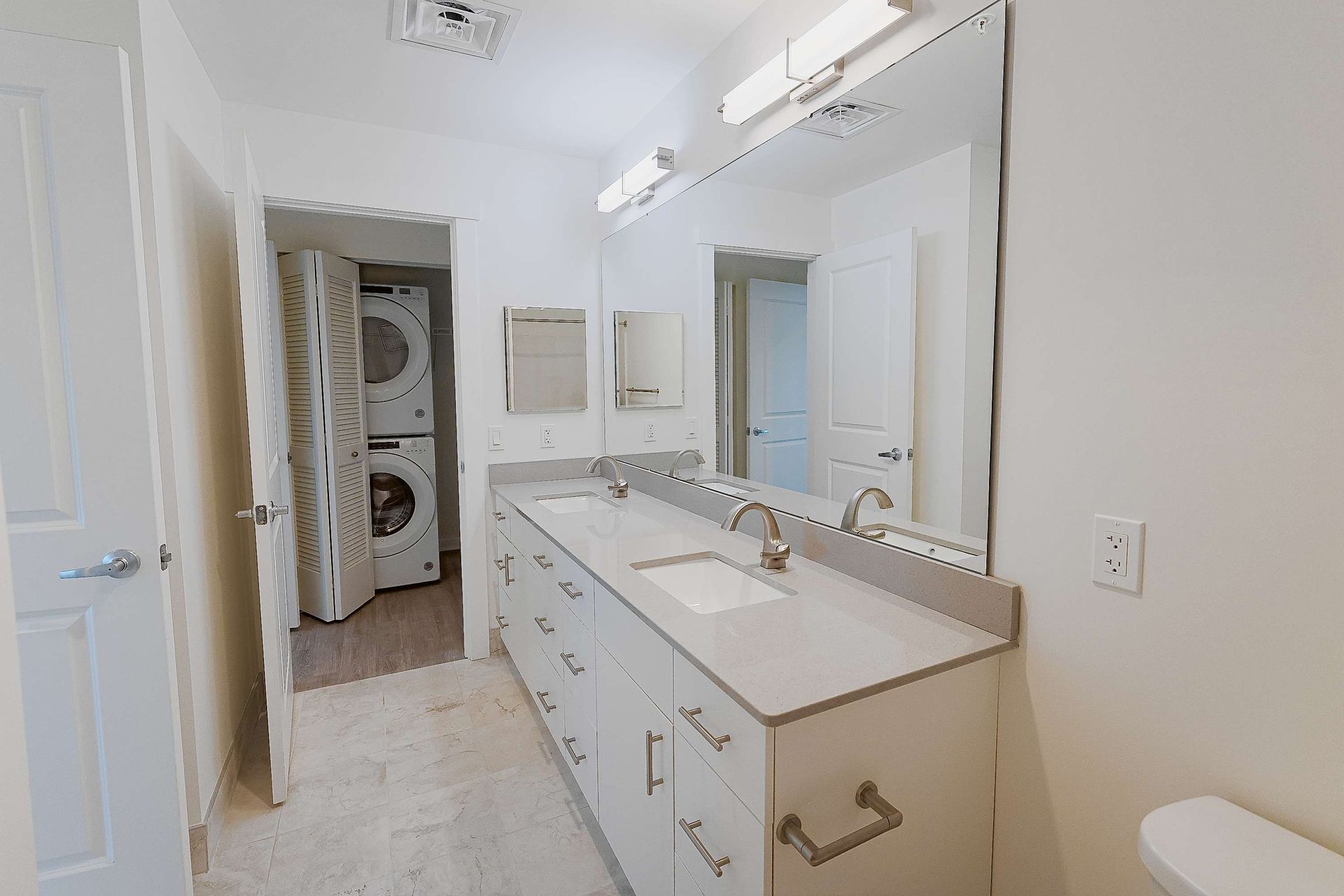 A bathroom with two sinks , a toilet and a washer and dryer.