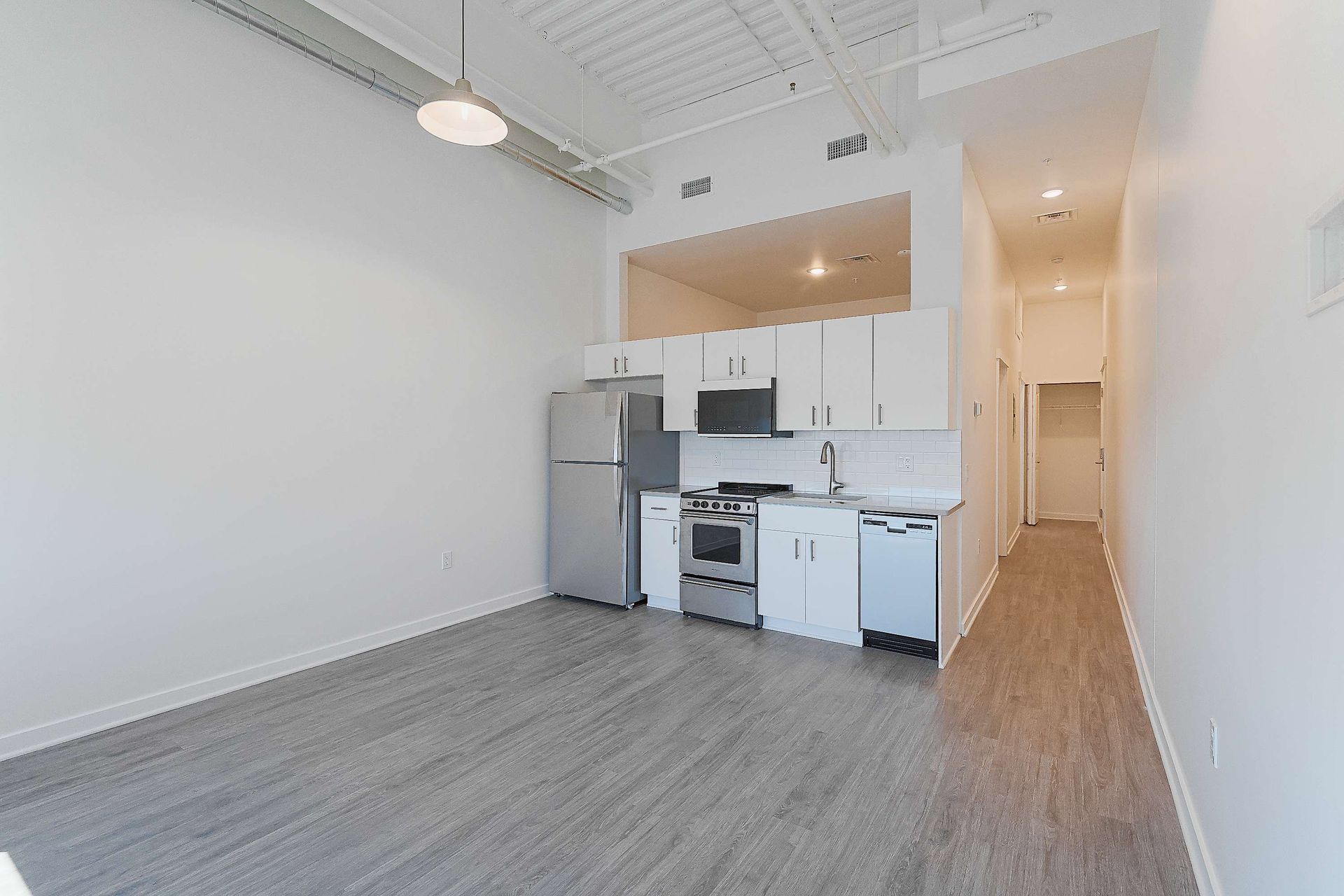 An empty apartment with a kitchen and a living room.