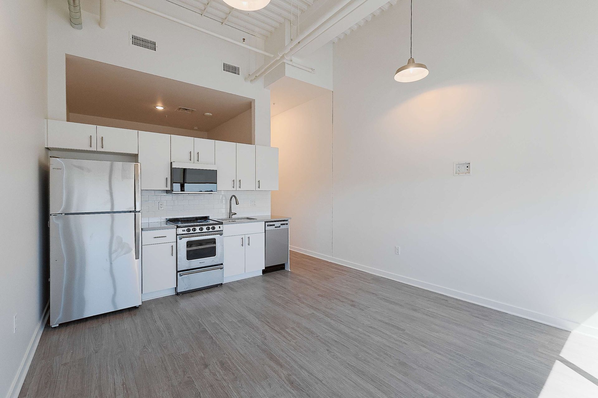 An empty kitchen with stainless steel appliances and white cabinets.