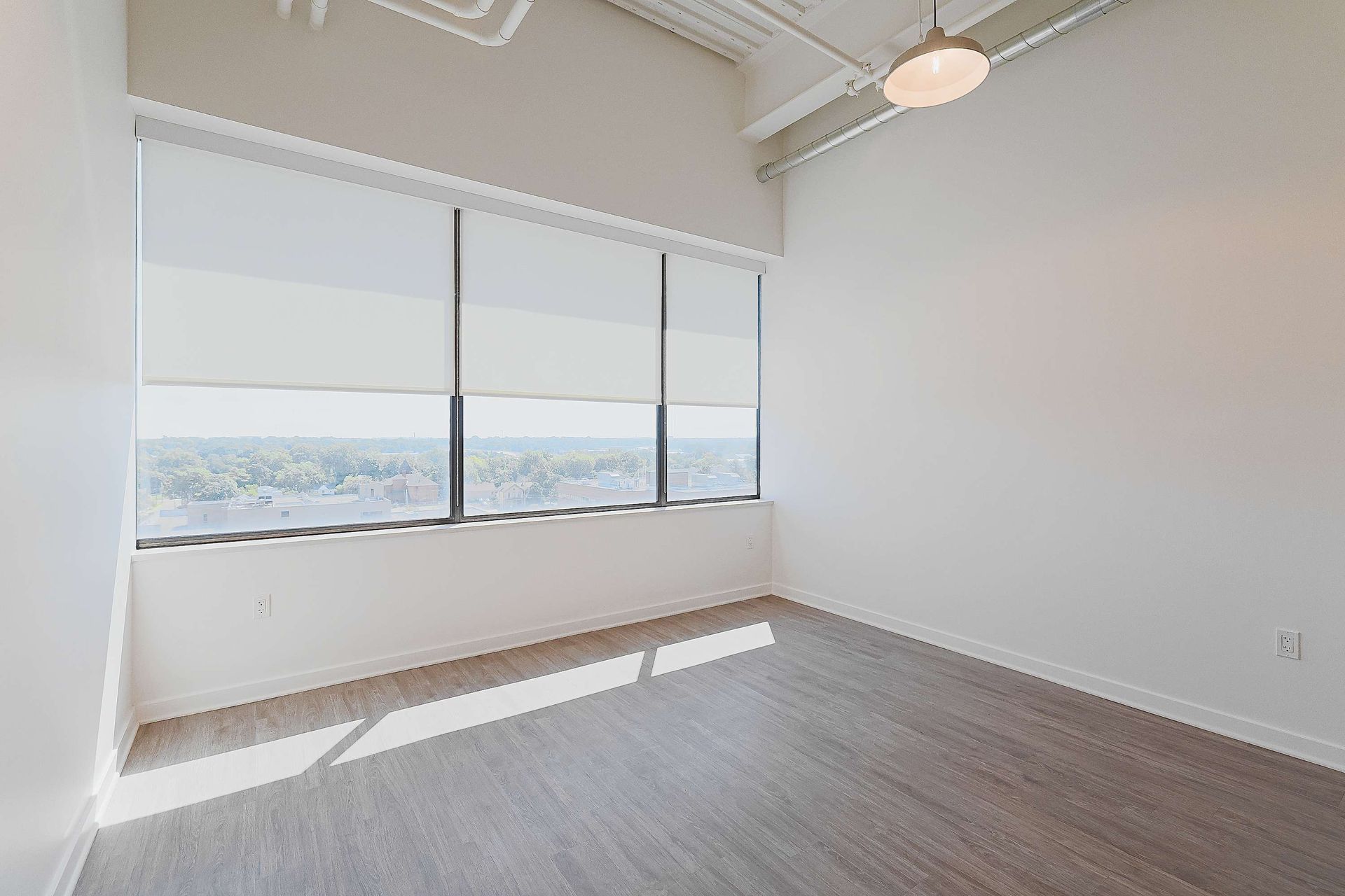 An empty room with a large window and a ceiling fan.