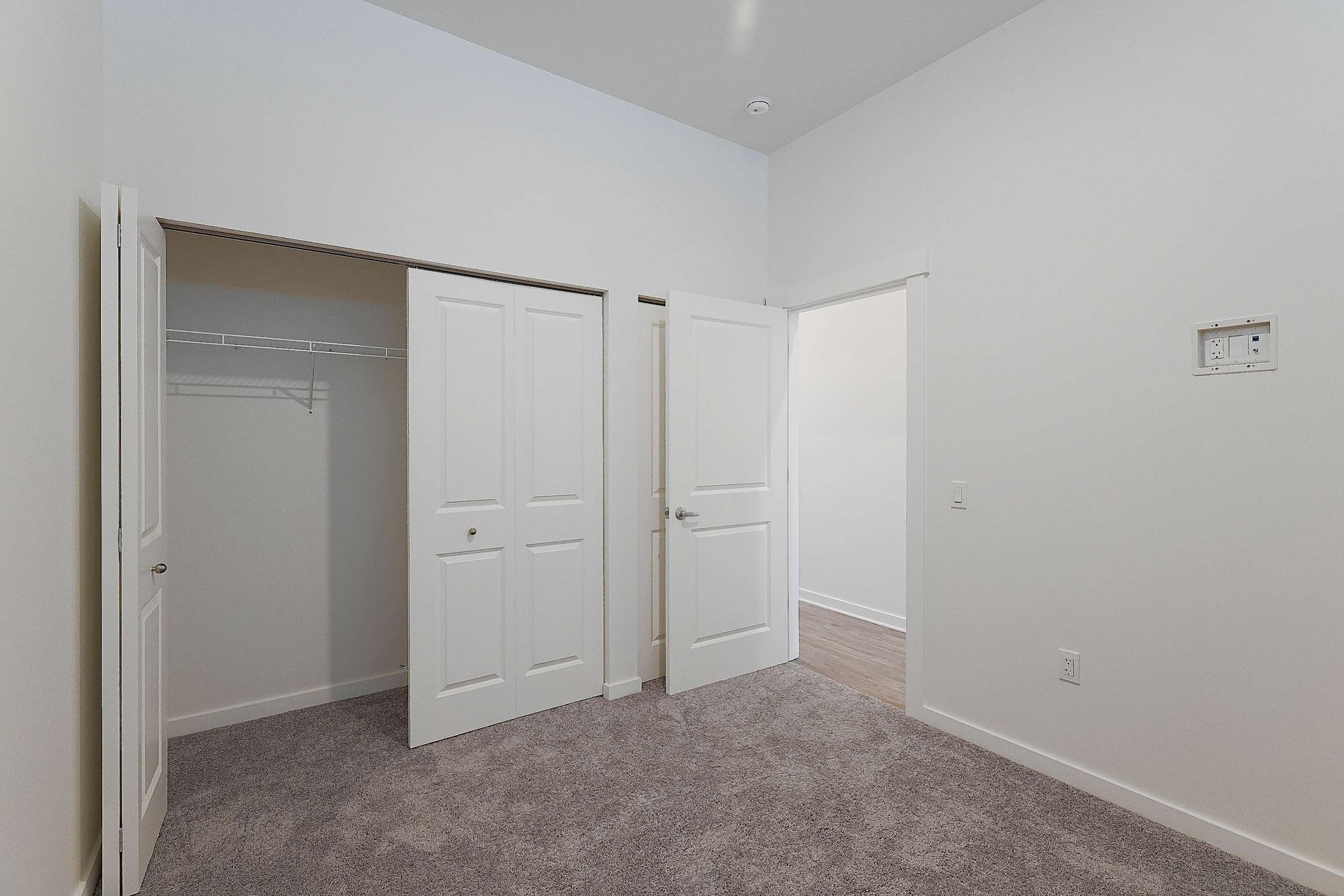 An empty bedroom with a walk in closet and a carpeted floor.