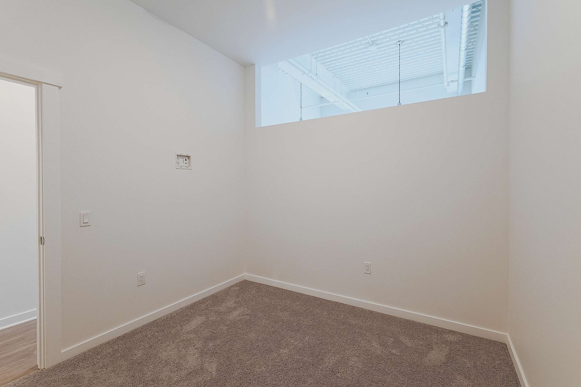An empty room with a window and a carpeted floor.