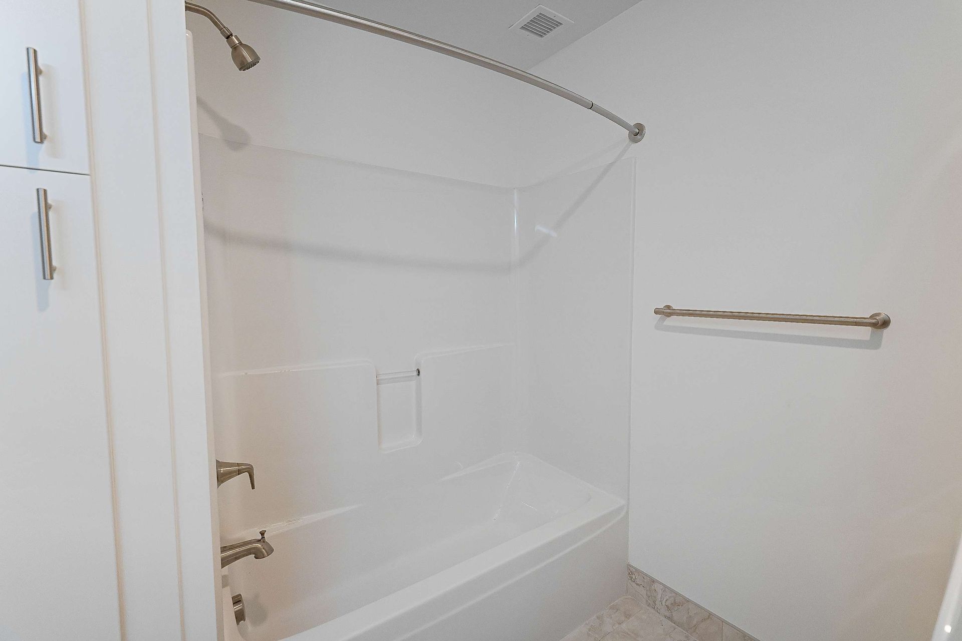 A bathroom with a bathtub , shower , and cabinets.