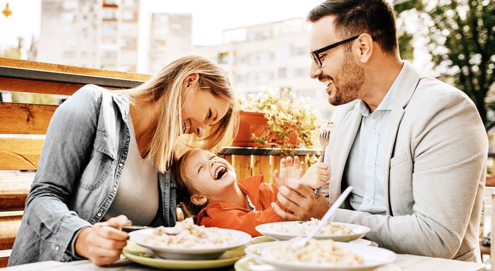 A family is sitting at a table eating food together.