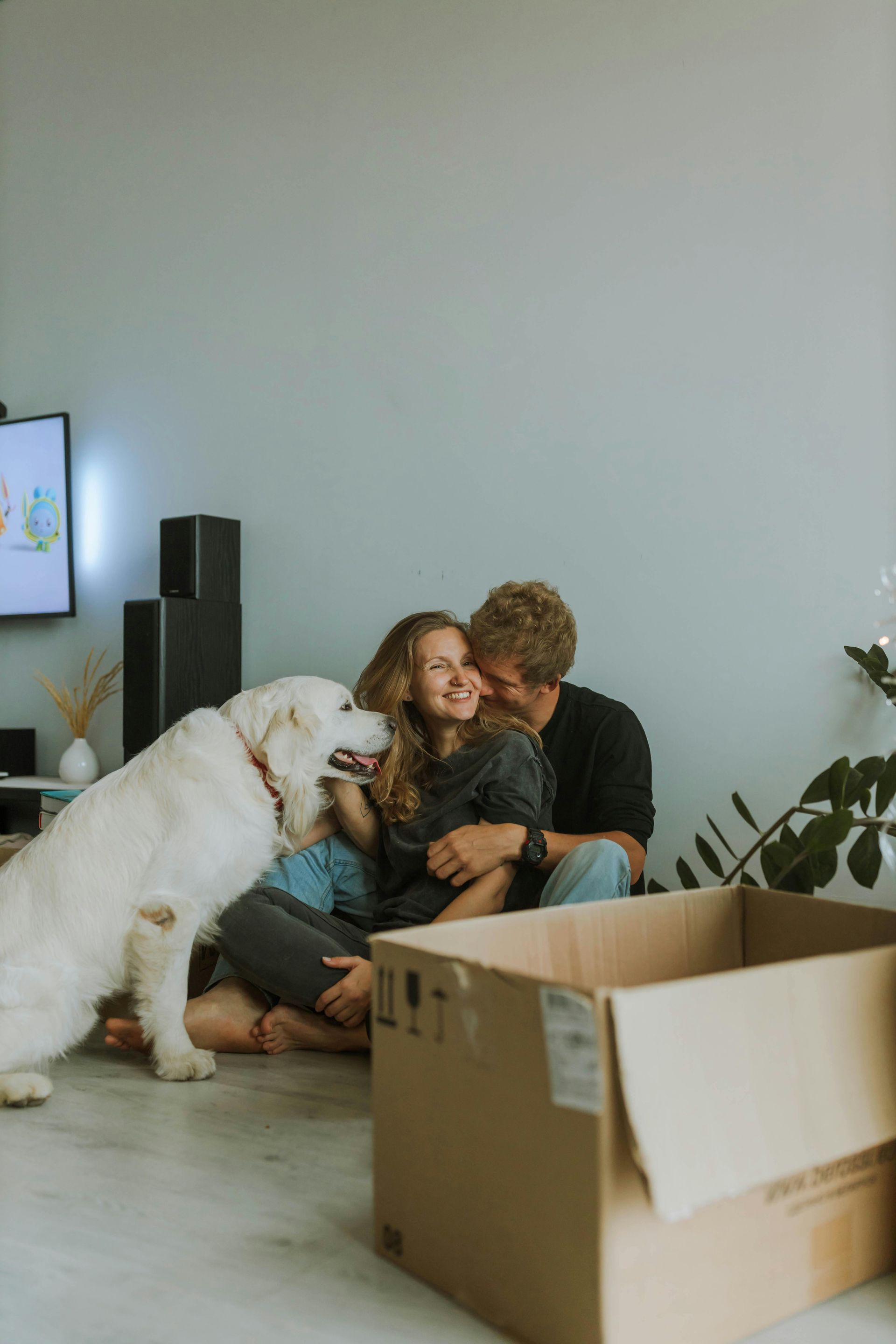 A man and a woman are sitting on the floor with a dog.