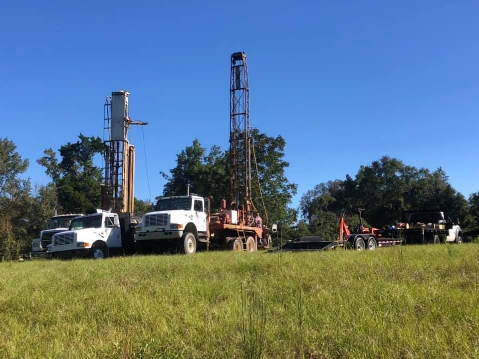 Drilling rigs in a grassy field under a blue sky, likely for well construction or exploration.