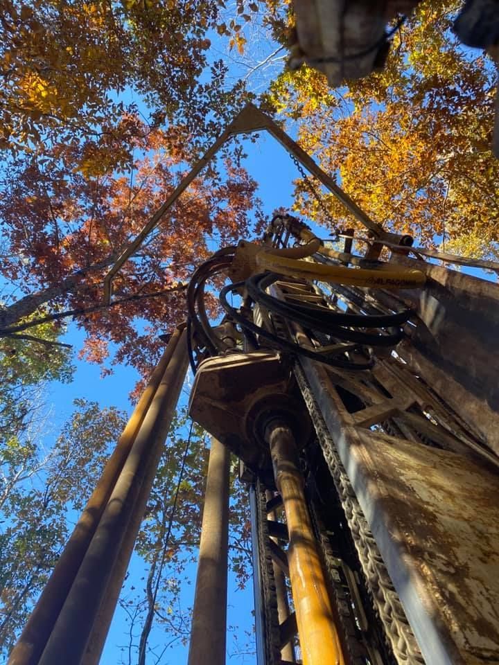 Drilling rig against a blue sky, surrounded by trees with autumn leaves.