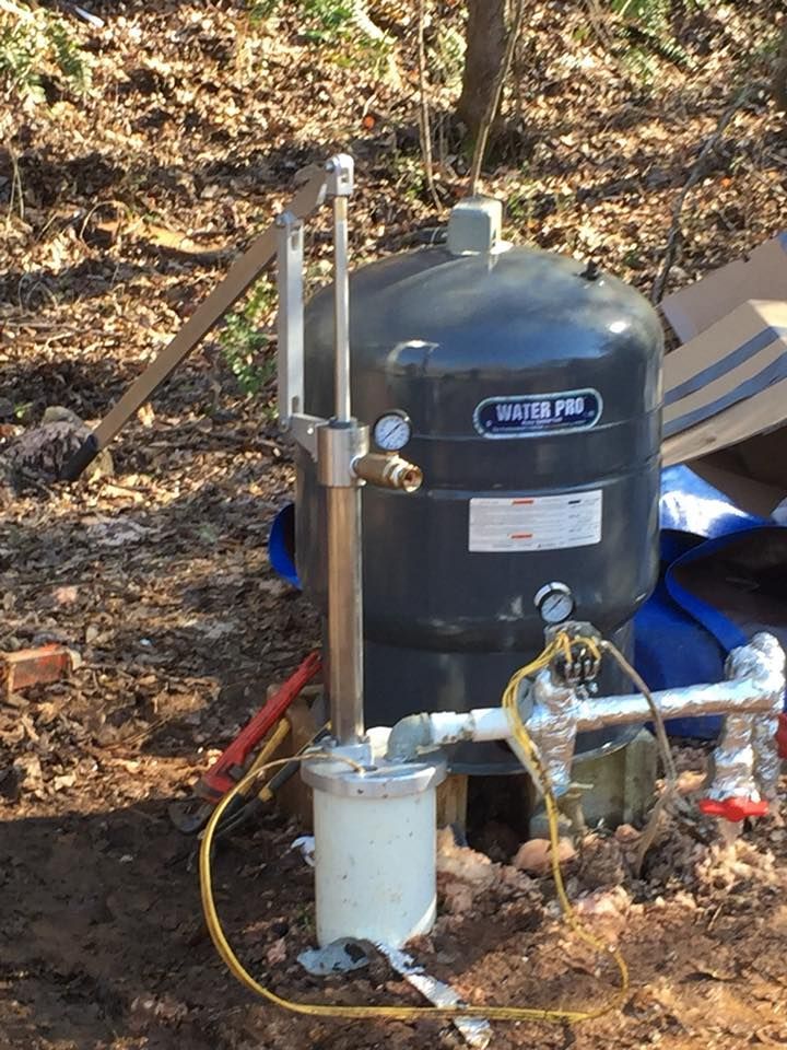 Well pump system with pressure tank in a wooded area.