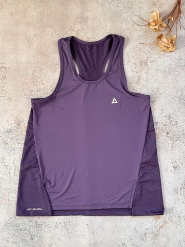 Camiseta deportiva sin mangas de color morado extendida sobre una superficie beige con textura.