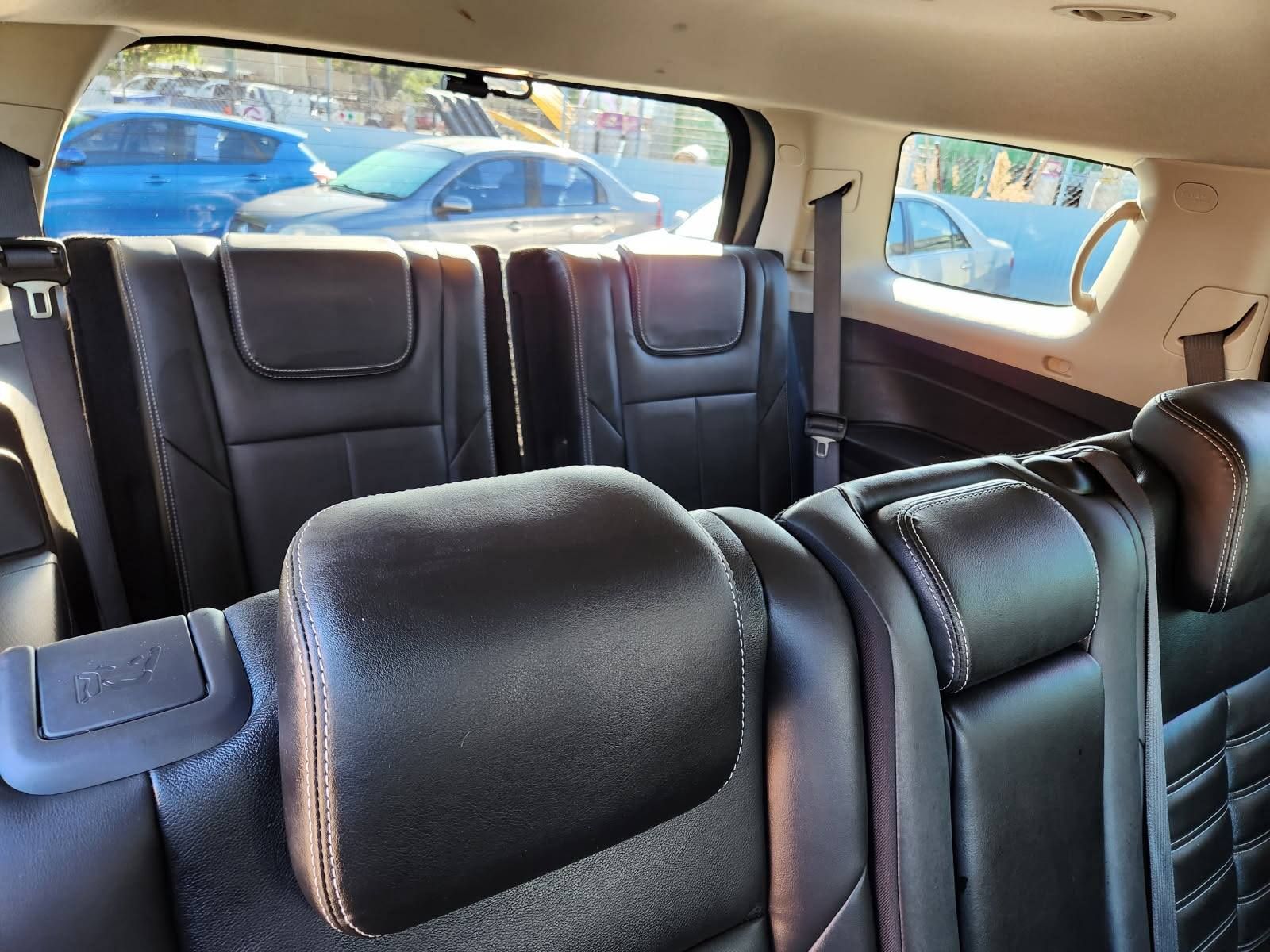 Black leather car seats in the back of a vehicle, with headrests and windows showing cars outside.
