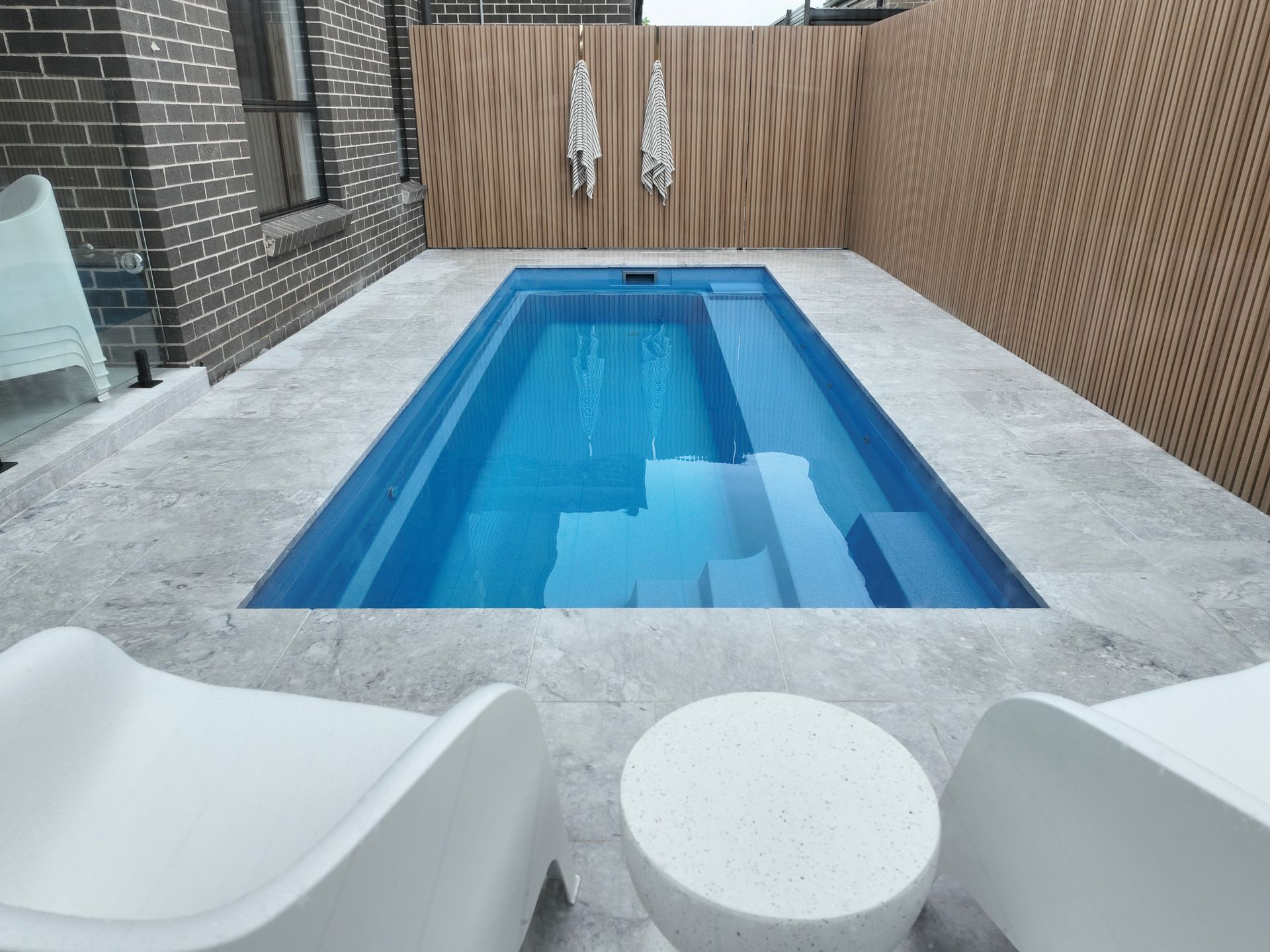 A Rectangular Blue Swimming Pool Surrounded by Grey Stone Pavers — Billabong Pool Co in Smeaton Grange, NSW