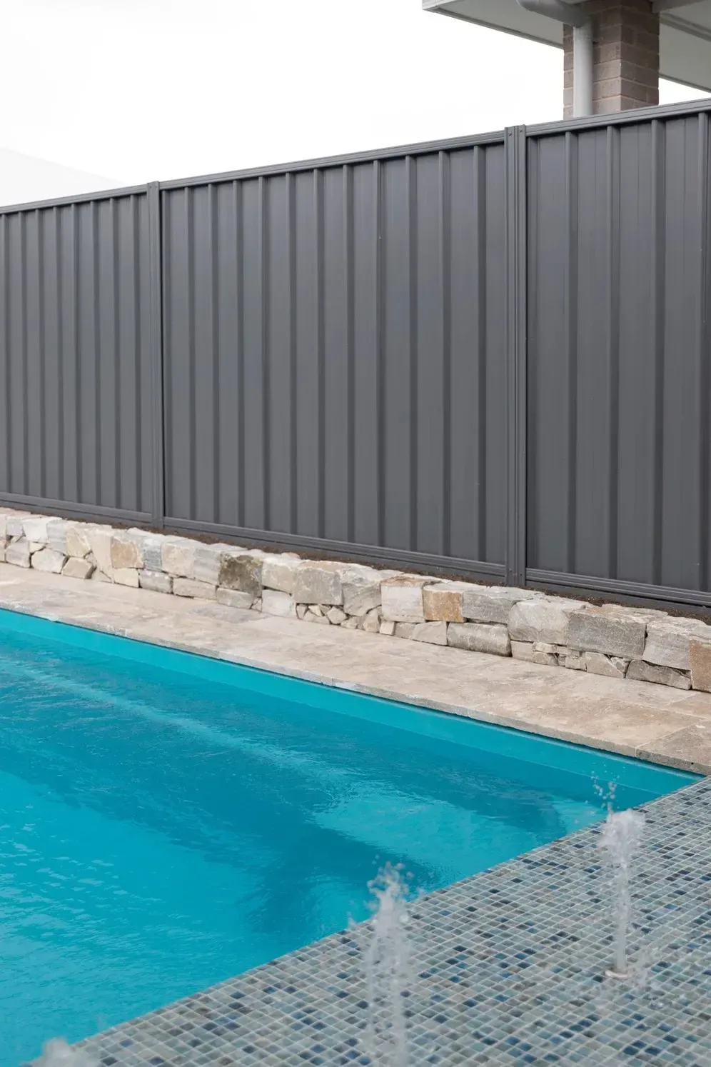 Backyard Pool With Gray Privacy Fence and Stone Border — Billabong Pool Co in Smeaton Grange, NSW