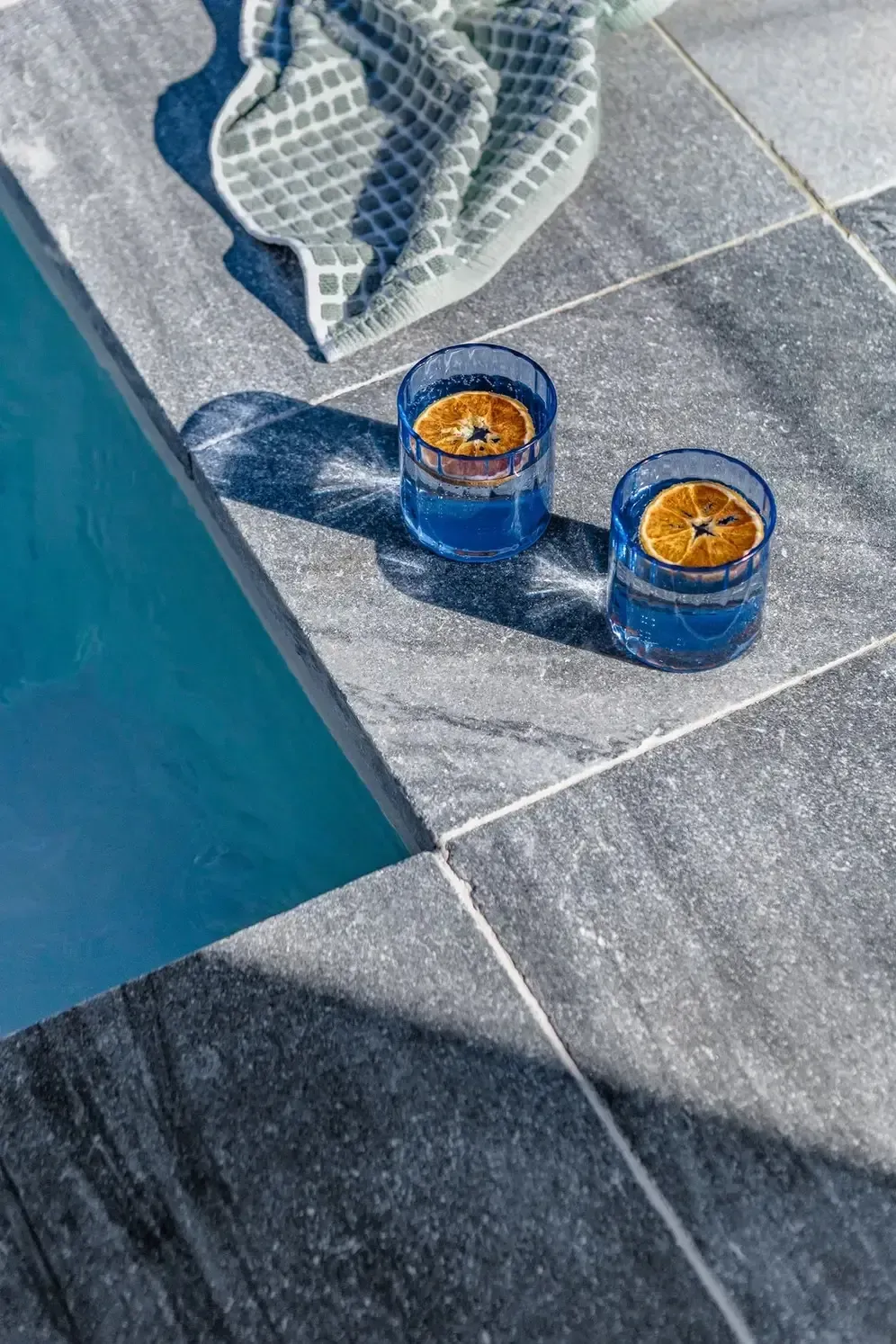 Two Blue Candles on a Tiled Poolside Ledge Beside Turquoise Water — Billabong Pool Co in Smeaton Grange, NSW