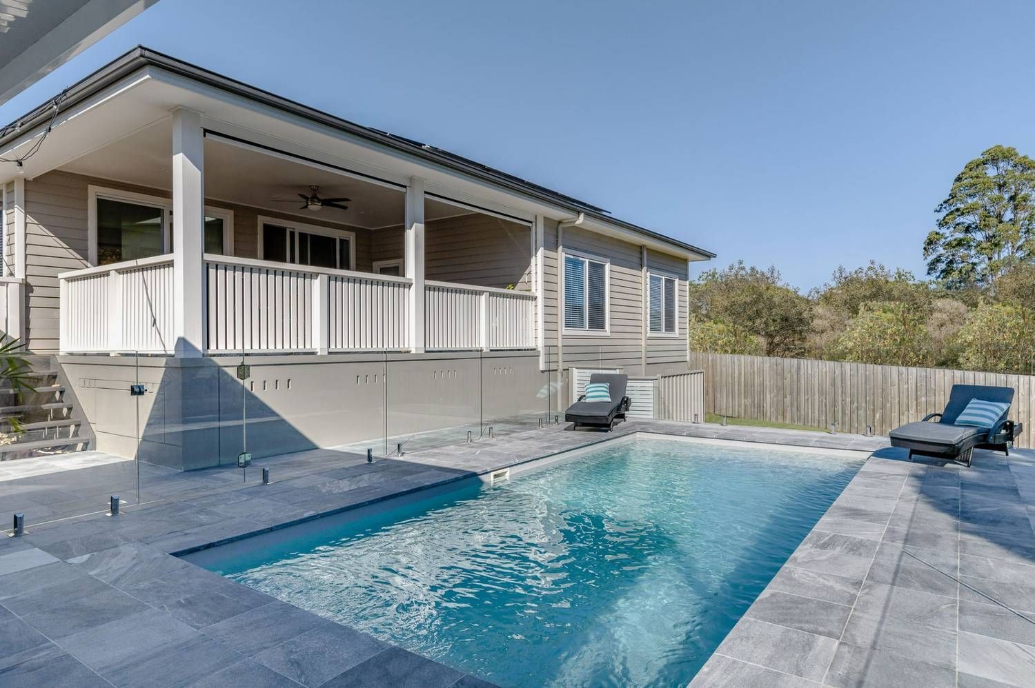 Backyard Pool Beside a White House With a Covered Porch and Two Lounge Chairs — Billabong Pool Co in Smeaton Grange, NSW