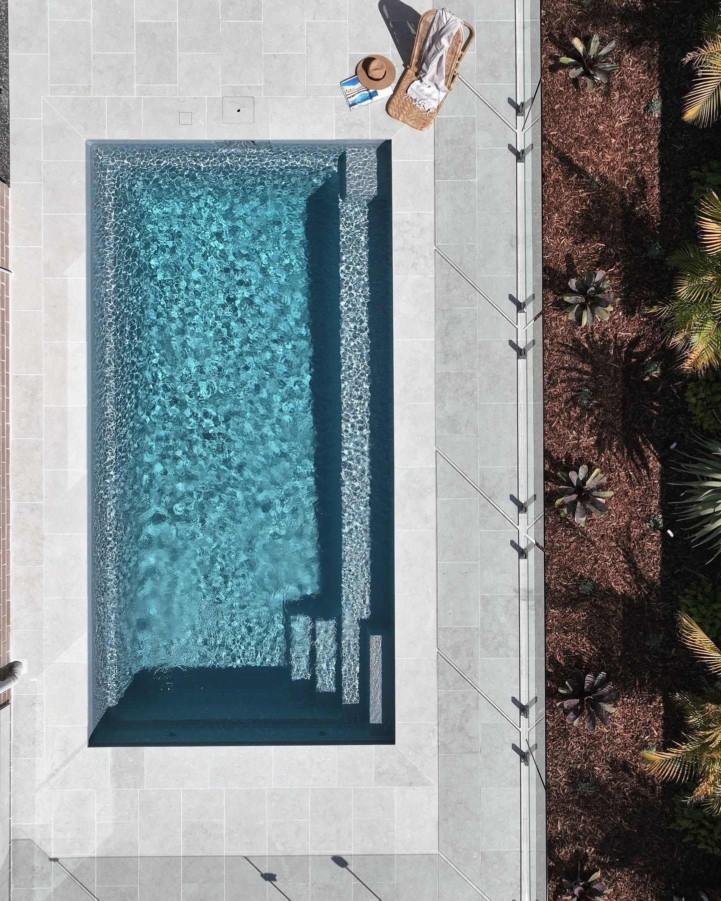 Top-down View of a Rectangular Blue Pool Beside a Patio With Lounge Chairs and Potted Plants — Billabong Pool Co in Wollongong, NSW