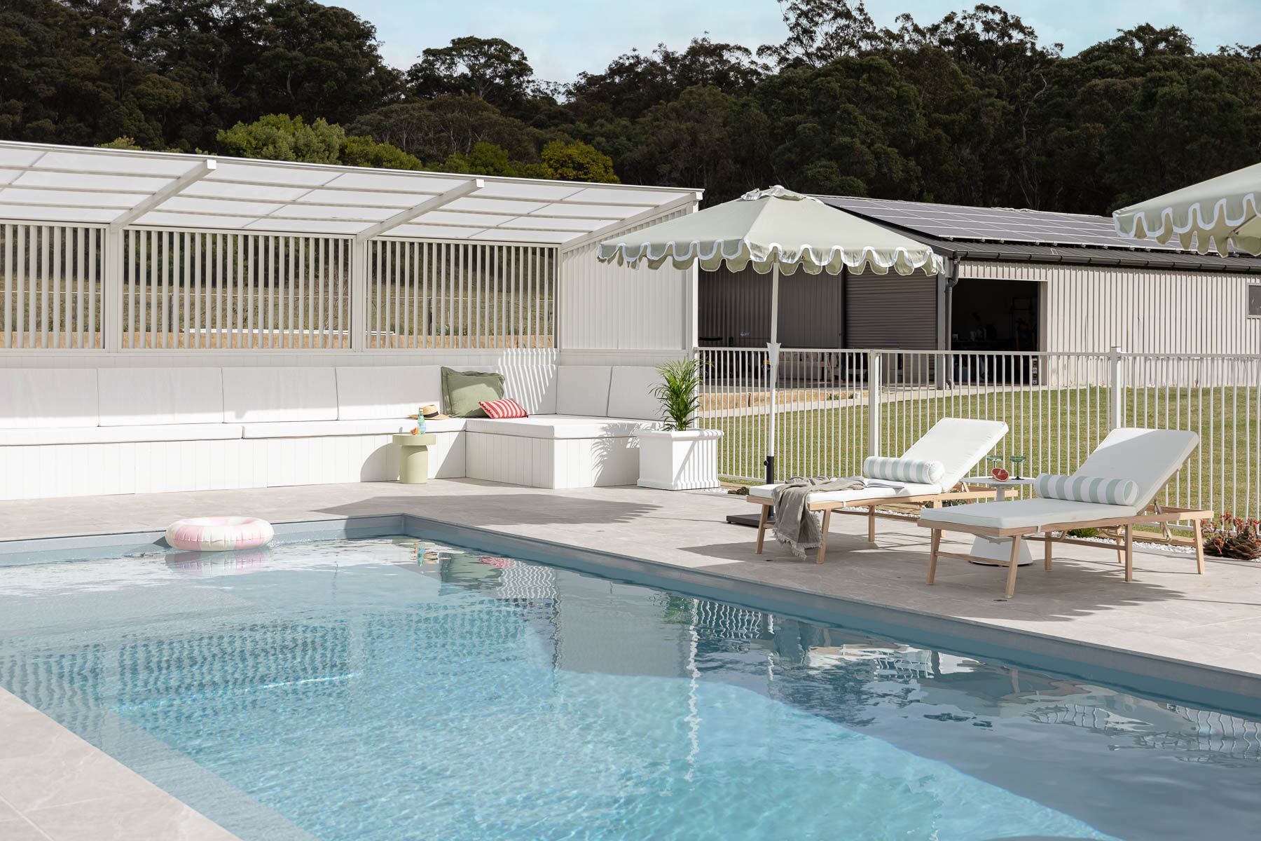 Poolside Patio With White Lounge Chairs, Umbrellas — Billabong Pool Co in Smeaton Grange, NSW