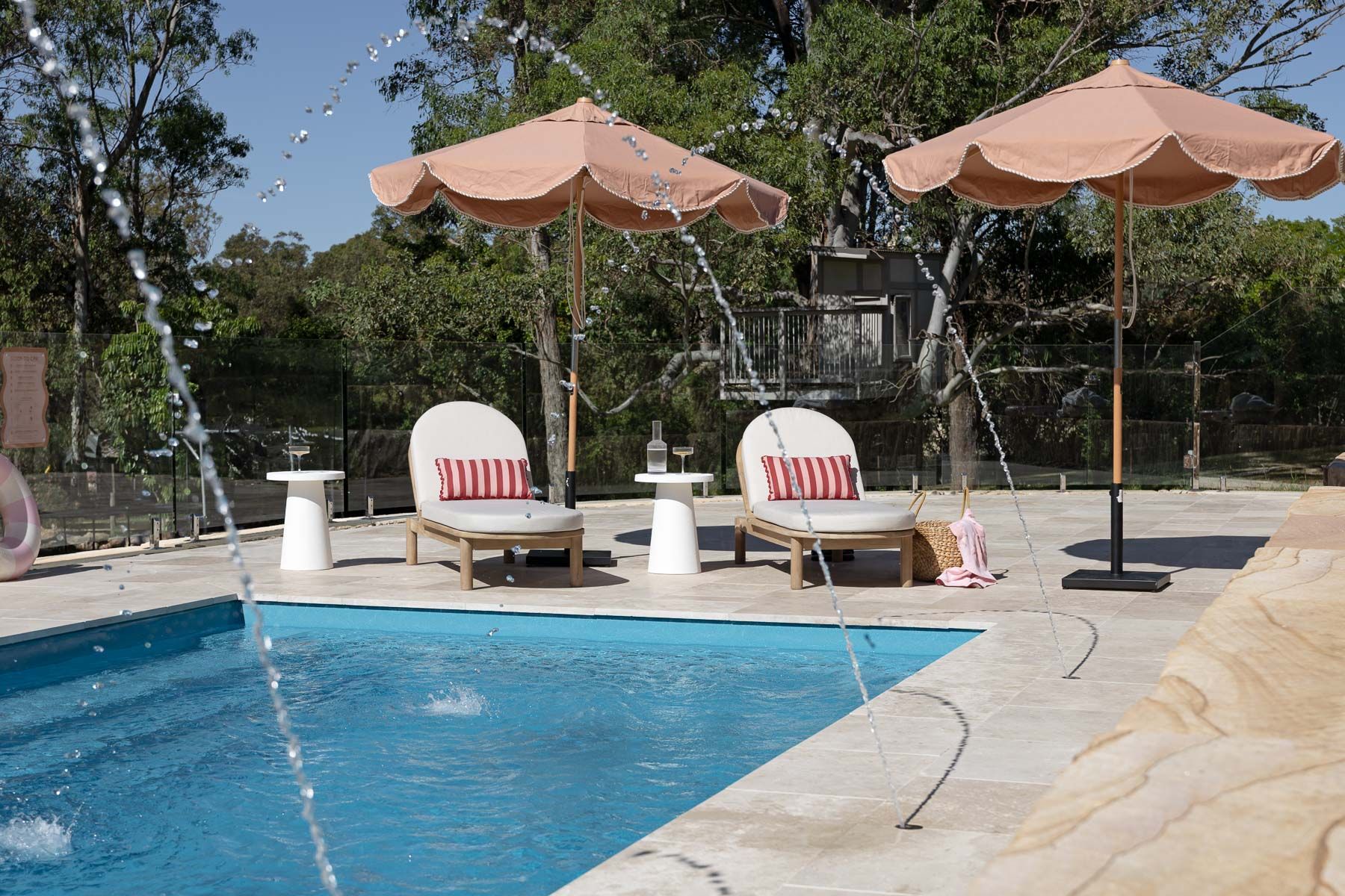 Poolside Lounge Chairs and Peach Umbrellas Beside a Blue Swimming Pool — Billabong Pool Co in Smeaton Grange, NSW