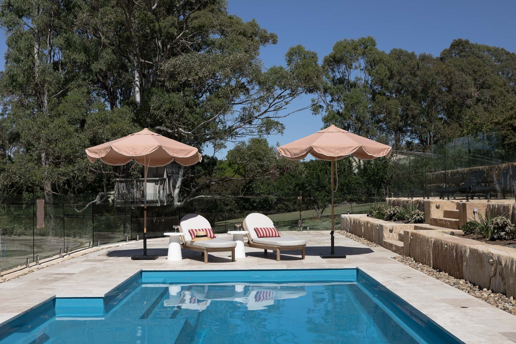 Backyard Pool With Two Lounge Chairs, Peach Umbrellas, and Trees in the Background — Billabong Pool Co in Smeaton Grange, NSW