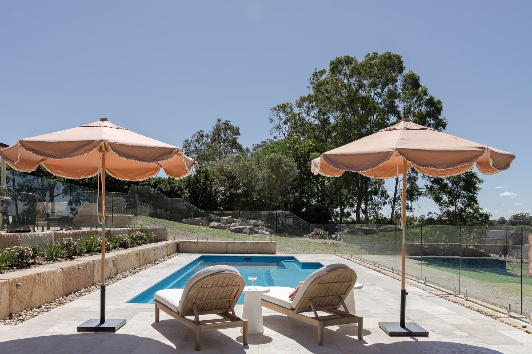Poolside Lounge Chairs and Umbrellas Beside a Small Backyard Pool on a Sunny Day — Billabong Pool Co in Smeaton Grange, NSW