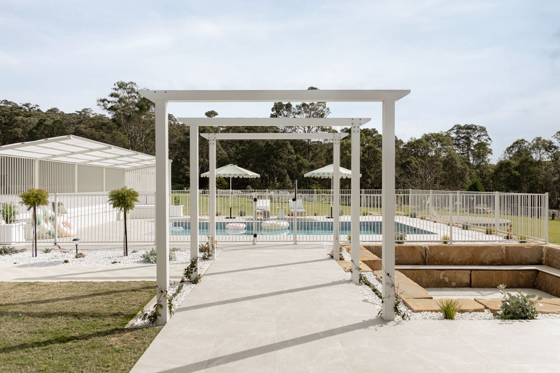 White Pergola Walkway Leading to a Poolside Garden — Billabong Pool Co in Smeaton Grange, NSW