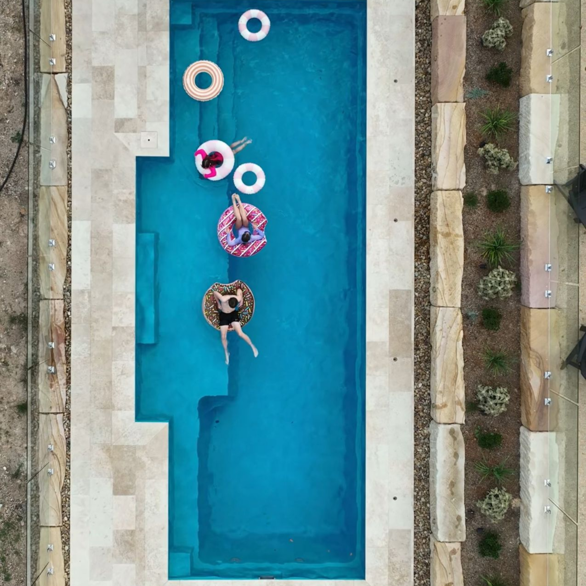 Overhead View of Three People Floating in a Narrow Blue Pool — Billabong Pool Co in Smeaton Grange, NSW