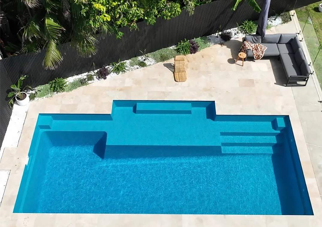 Blue Swimming Pool With Built-in Steps and Tan Patio Surrounded by Greenery — Billabong Pool Co in Wollongong, NSW
