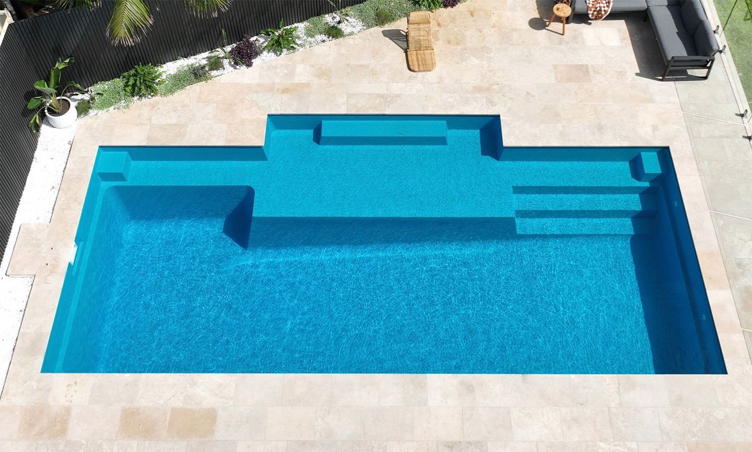 Swimming Pool With Blue Water, Surrounded By Beige Stone — Billabong Pool Co in Smeaton Grange, NSW