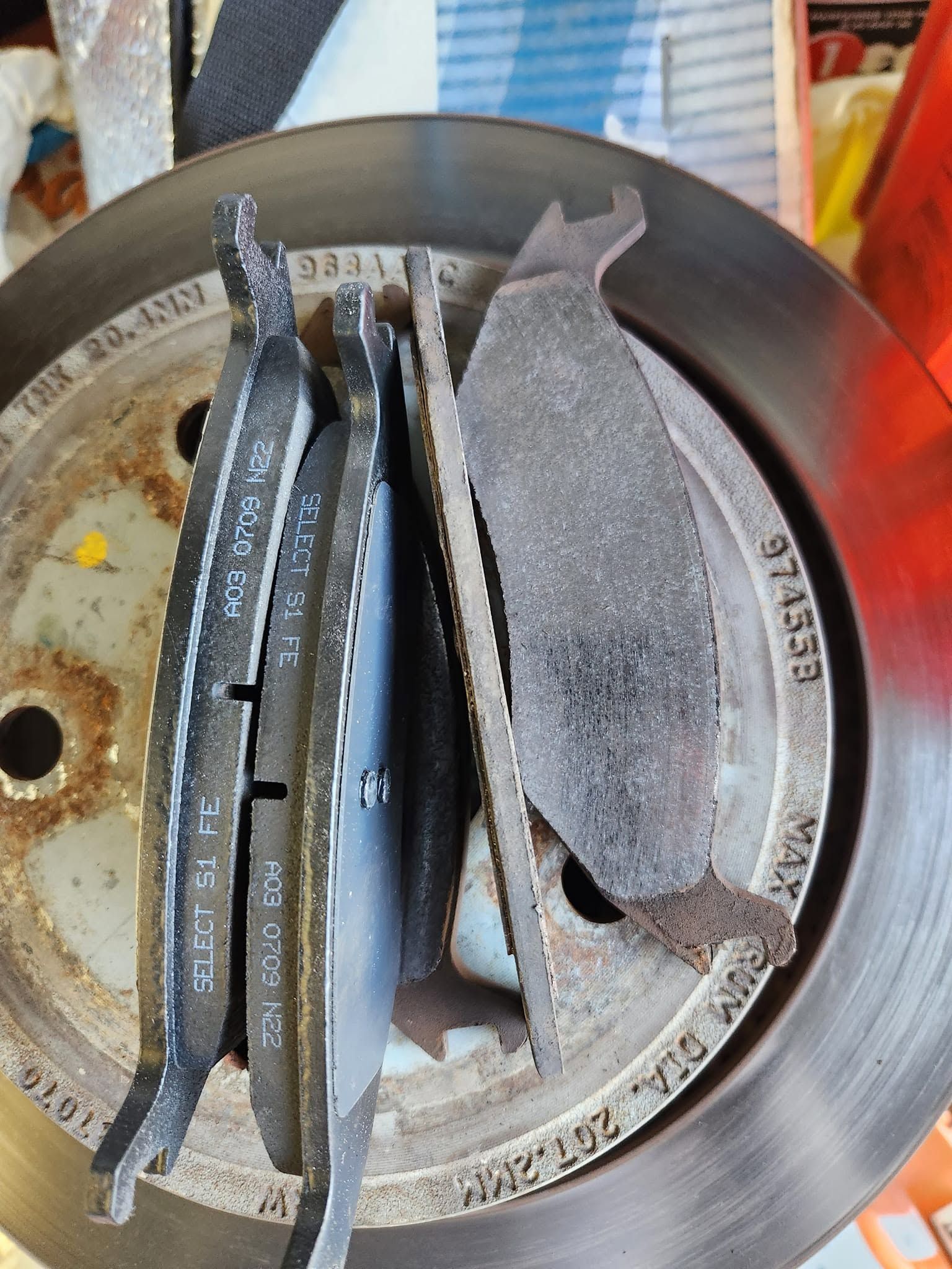 Close-up of worn brake pads and a brake rotor, showing heavy dust and wear.