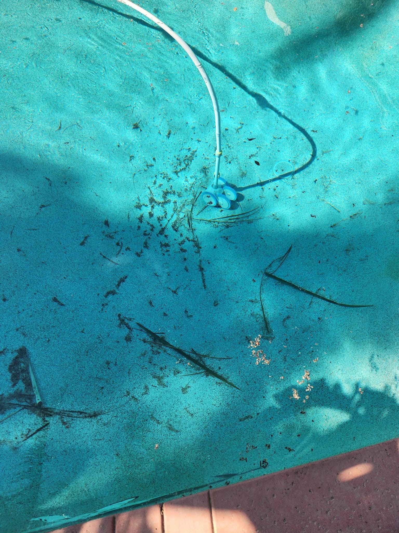 Turquoise fabric with dirt and scratches, partially covering a pink surface
