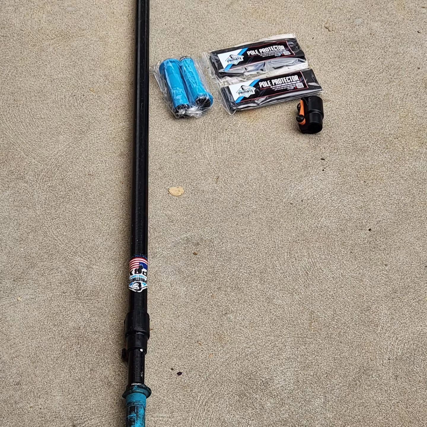 Black pole on concrete with blue accessories and two packaged items рядом