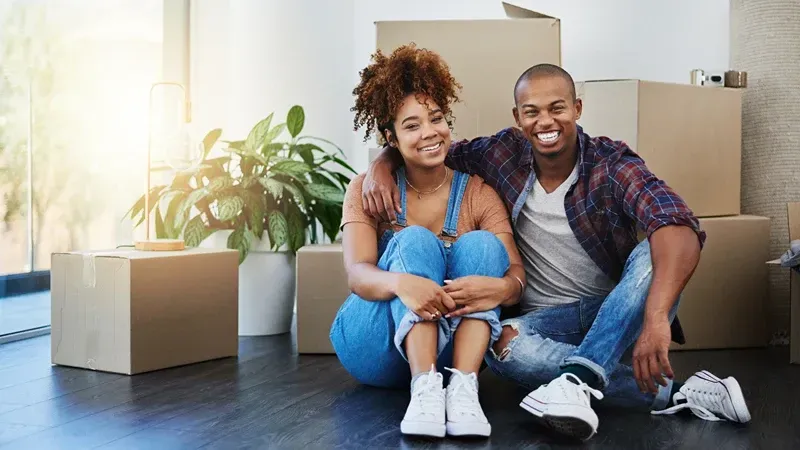 a man and a woman are sitting on the floor surrounded by cardboard boxes .