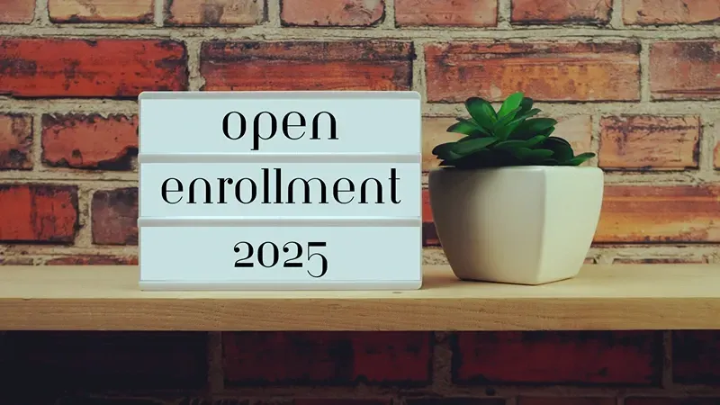 a sign that says `` open enrollment 2025 '' is on a shelf next to a potted plant .
