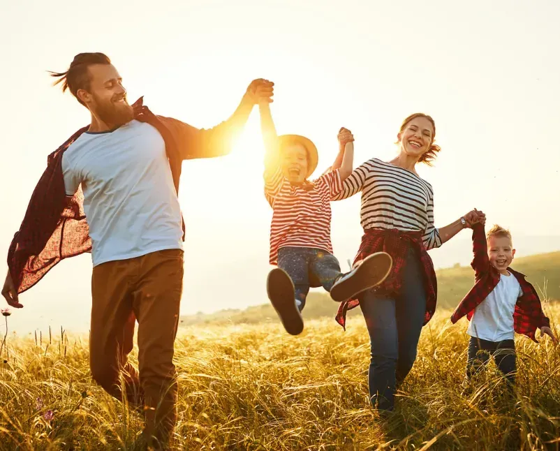 Parents and children running through a field at sunset, representing family health insurance plans