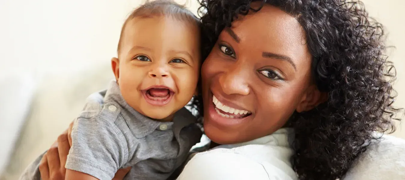 Smiling mother holding her baby, representing Affordable Care Act (ACA) Marketplace health plans for families