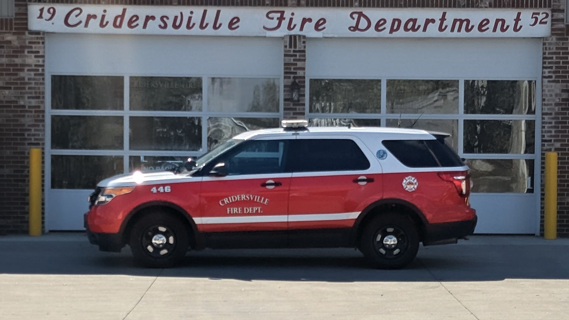 Red and white Cridersville Fire Department SUV parked in front of the fire station with closed garage doors.