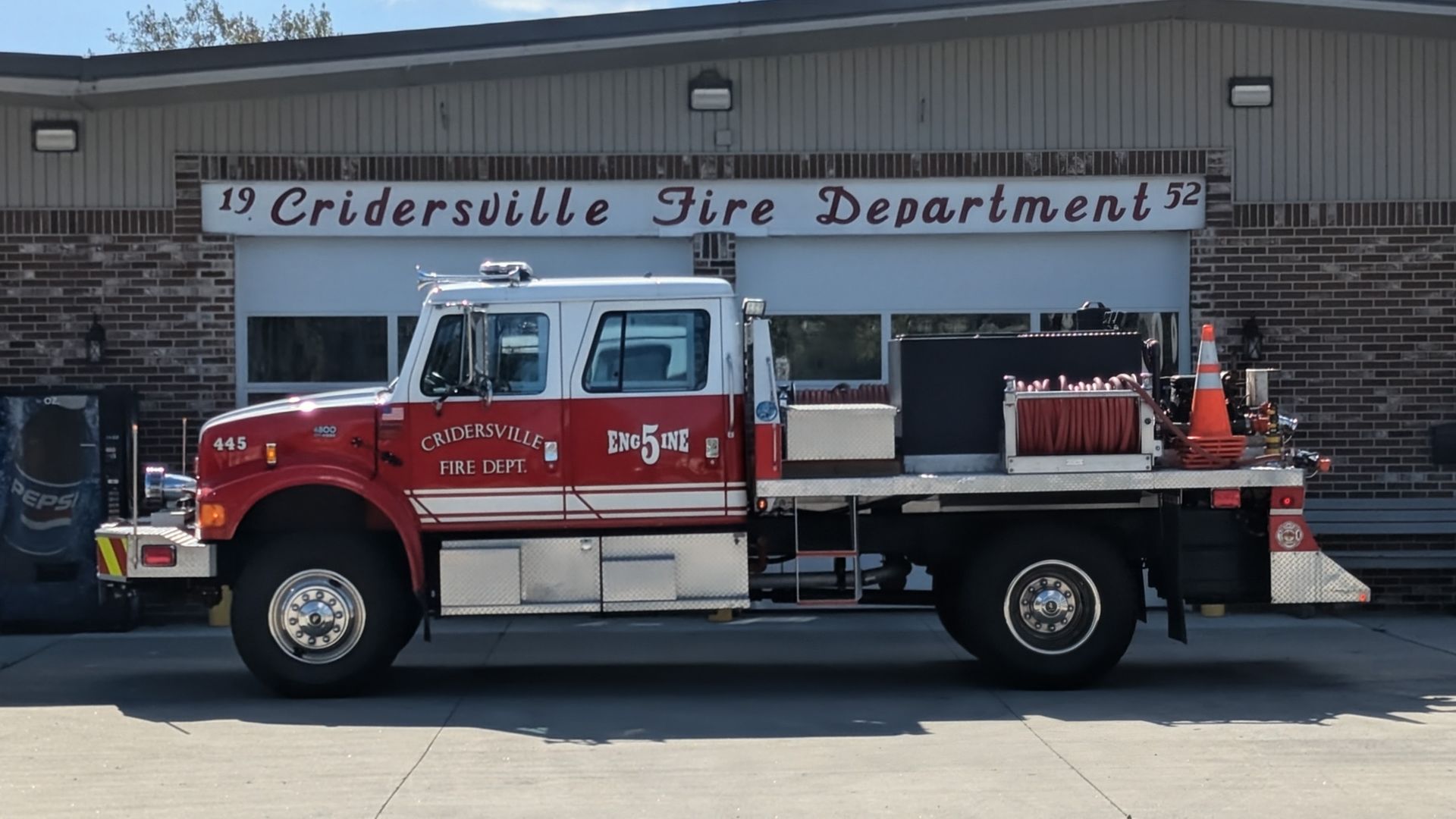 Fire truck parked in front of Cridersville Fire Department building. Red and white truck, daytime.