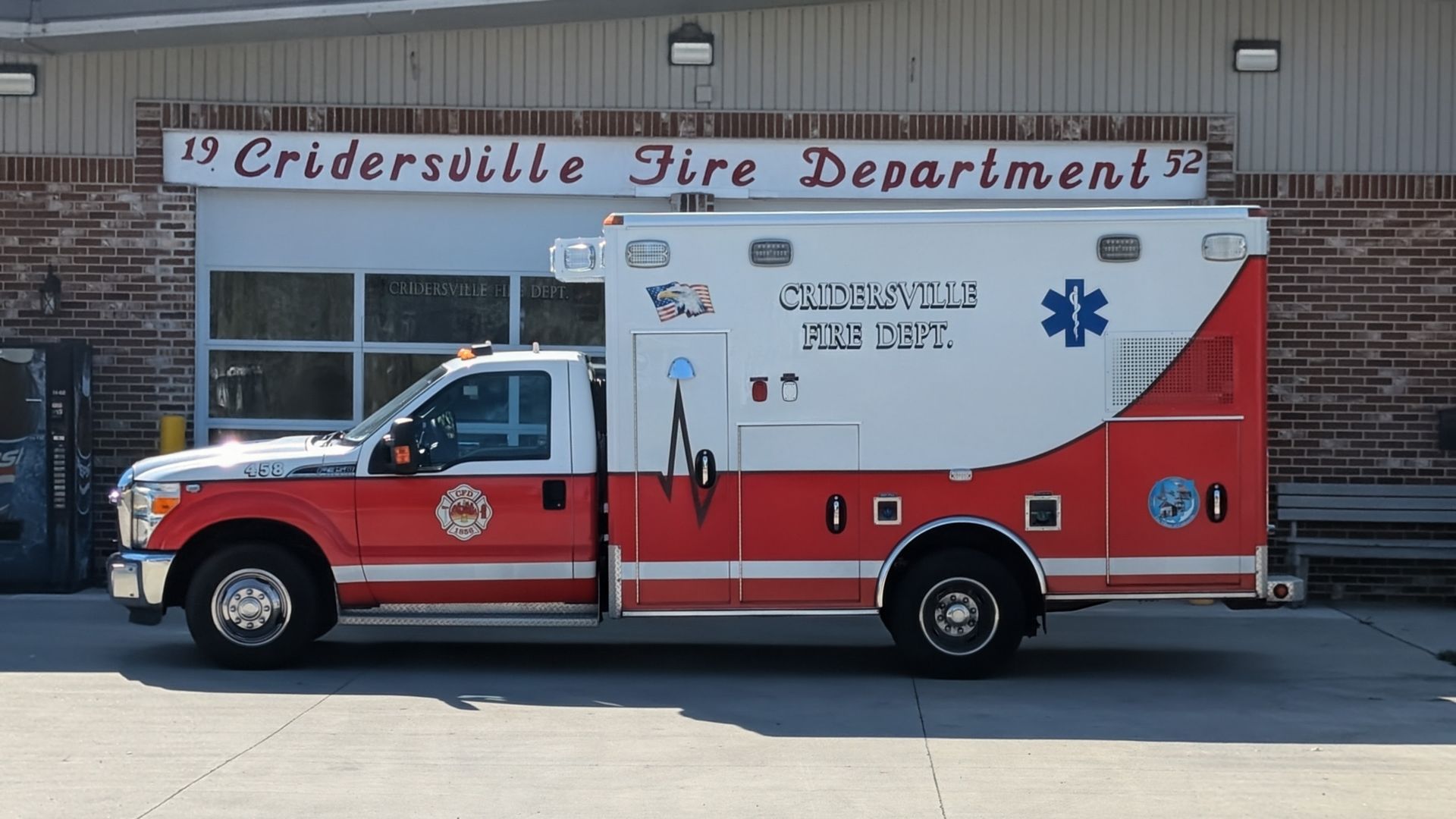 Ambulance from Cridersville Fire Department parked in front of its station, red and white with blue star.