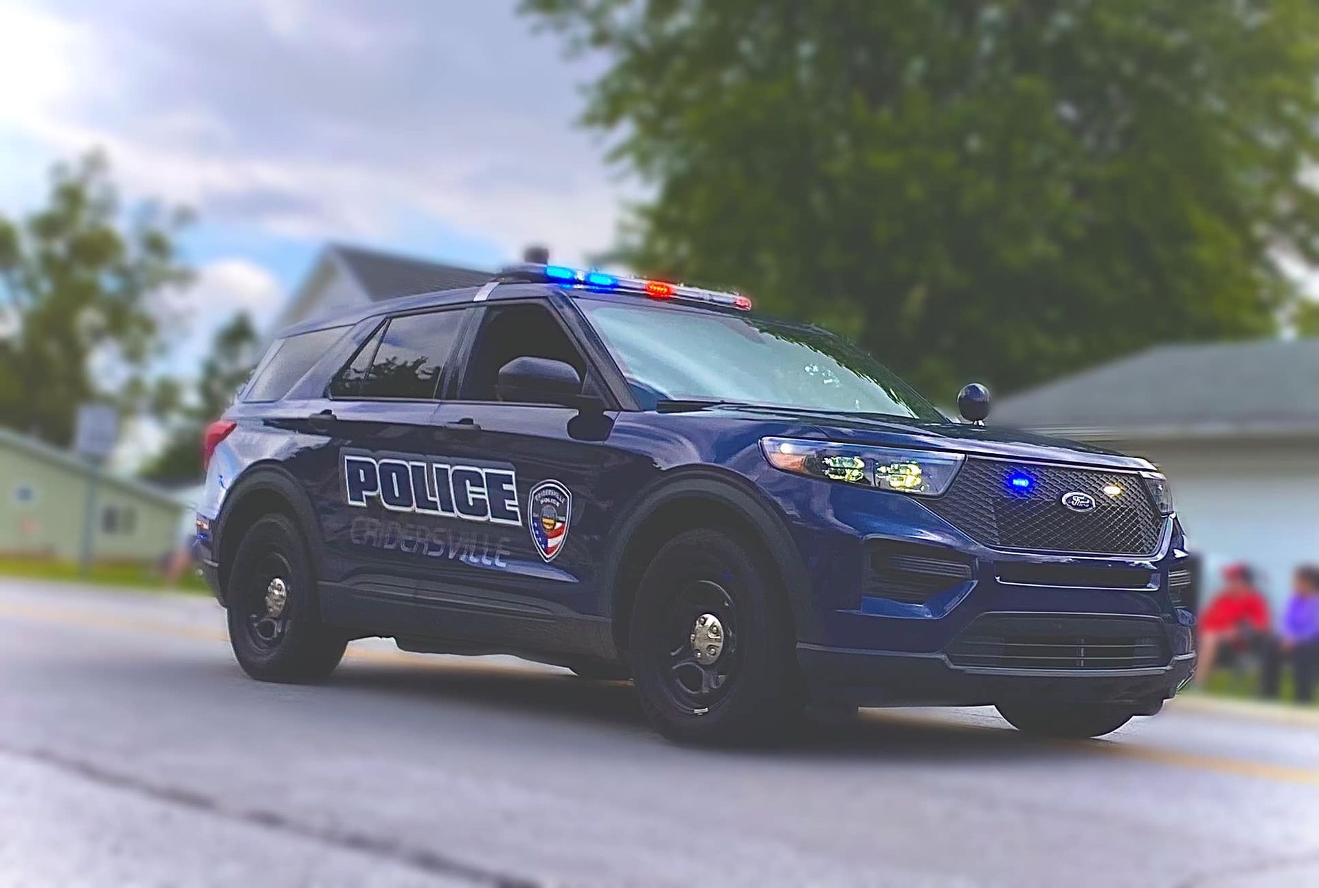 Dark blue police SUV with flashing lights.