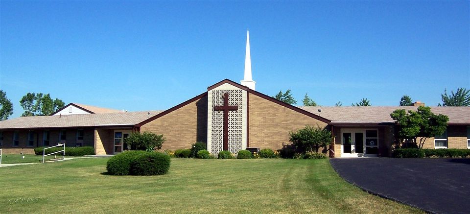Church building with steeple, cross, and lawn.