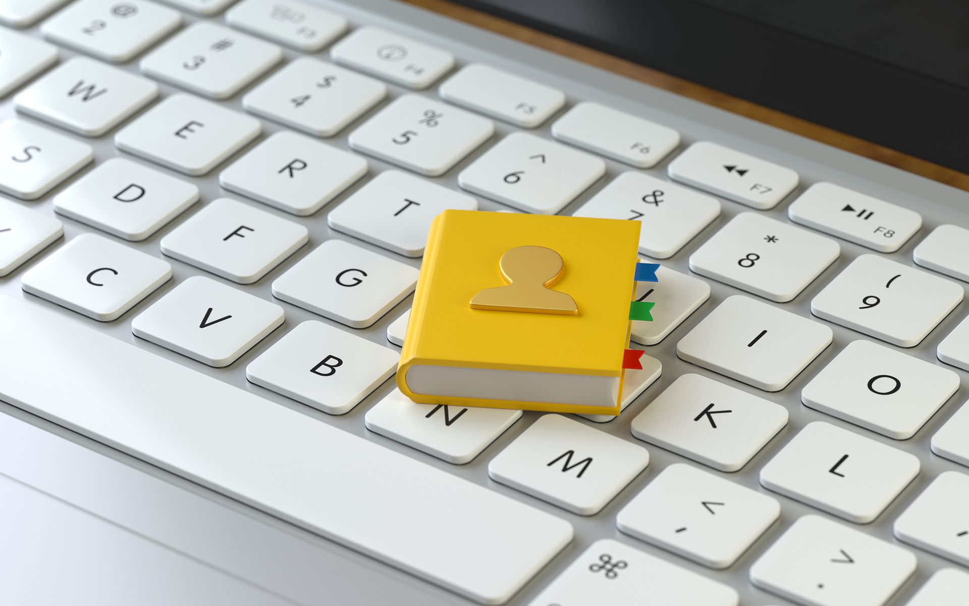 Yellow address book on a white laptop keyboard with colored tabs.