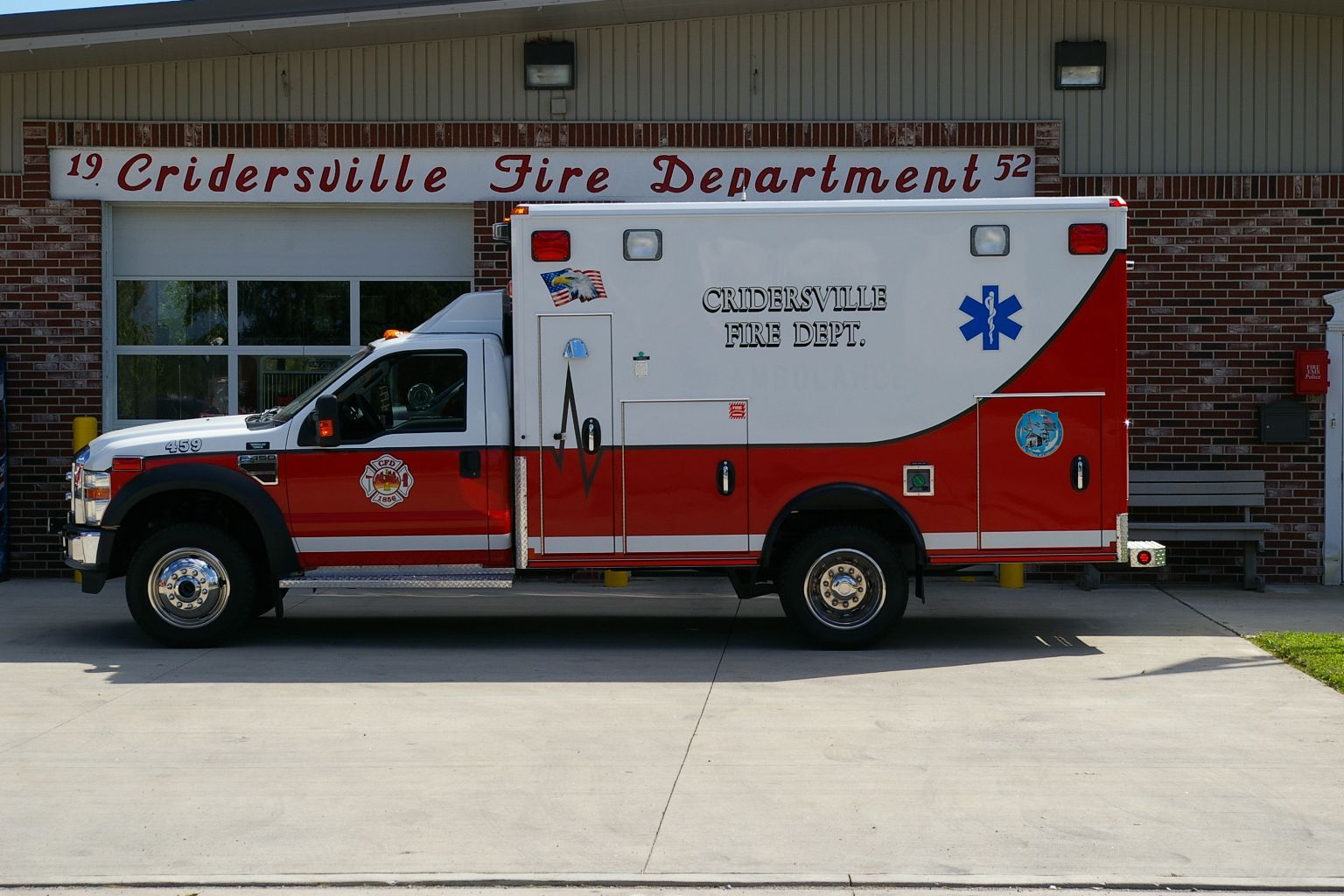 Ambulance from Cridersville Fire Department, red and white, parked in front of the station.