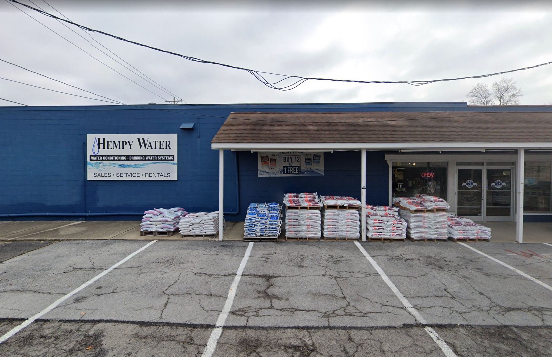 Blue-painted building with pallets of supplies in front. Sign reads