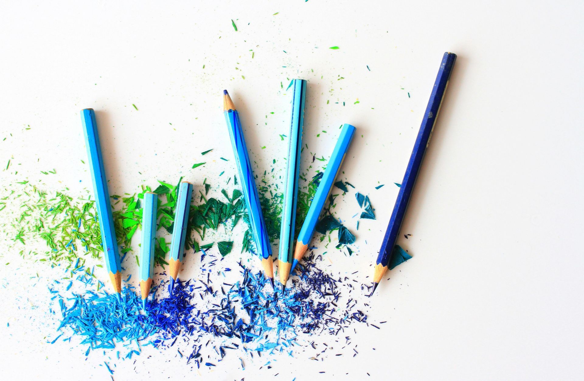 Blue pencils and shavings on white background.