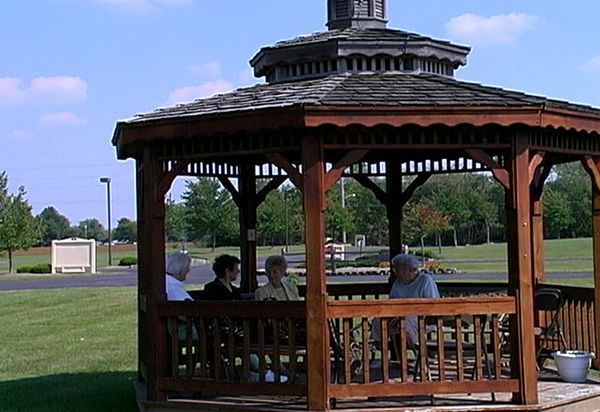 People sitting in a wooden gazebo on a sunny day.