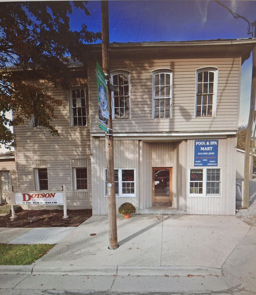 Two-story light-colored building with large windows. Signs for