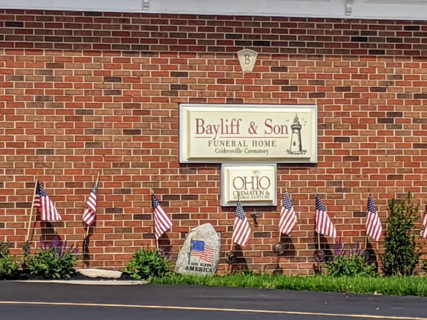 Bayliff & Son Funeral Home sign on a brick building with American flags and Ohio license.