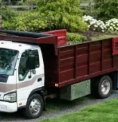 White and red dump truck parked on grass in a landscaped yard